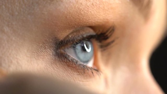 Closeup of woman's face applying concealer under eye with beauty blender sponge - video in slow motion