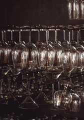 raws of glasses for a margarita, martini, grog and liqueur hanging upside down in bar at...