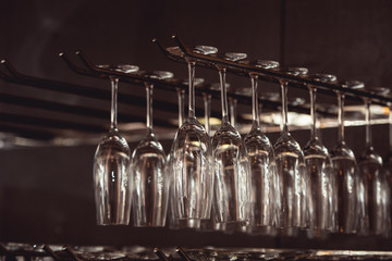 raws of glasses for a margarita, martini, grog and liqueur hanging upside down in bar at...