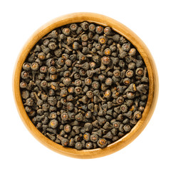 Dried cassia buds in wooden bowl. Unopened flowers of the cassia tree, picked before blooming. Cinnamomum cassia, also Chinese cassia or Chinese cinnamon. Macro photo closeup from above over white.