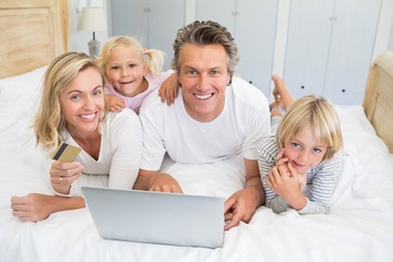 Happy family doing online shopping on laptop in the bed room