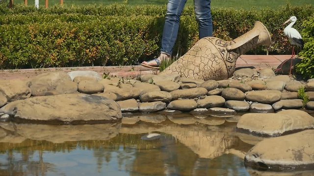 Cute woman strokes the cat near the pond in the garden