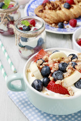 Bowl of yogurt with muesli and fresh fruits: strawberries, blueberries and bananas.