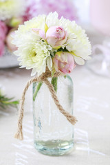 Tiny bouquet of roses and chrysanthemum daisies in glass vase.