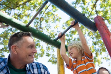 Obraz premium Low angle view of father and son playing on jungle gym