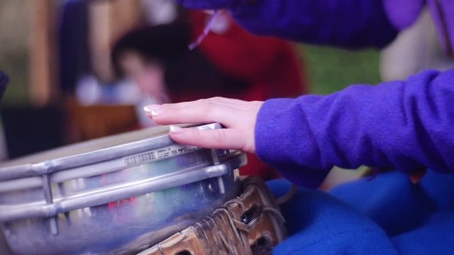 Woman is Playing on Small Drum Next to Microphone