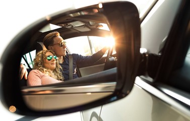 Couple reflecting in sideview mirror of car