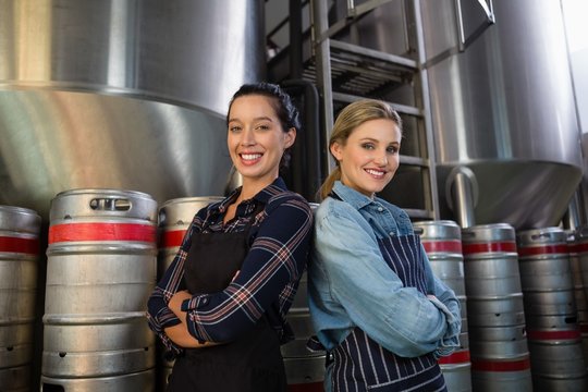 Portrait of smiling coworkers with arms crossed at brewery