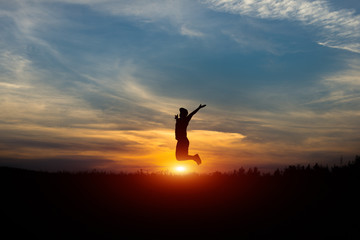 Silhouette of a cheerful man at sunset. Leap at sunset.