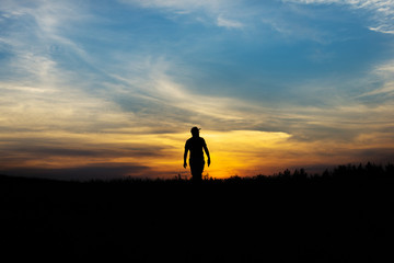 Silhouette of man at sunset. The man goes to the far side.