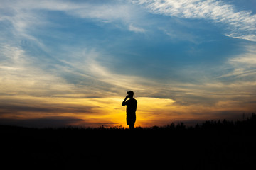Silhouette of the person talking on the phone at sunset.
