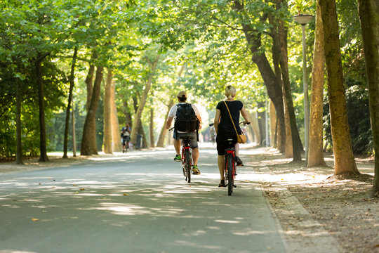 Man & woman biking in a sunny Vondelpark.