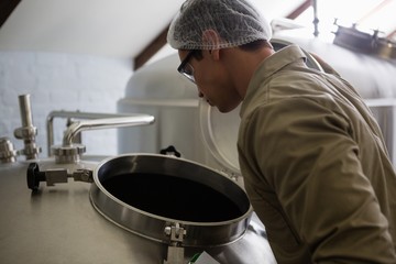 Worker looking into storage tank at brewery