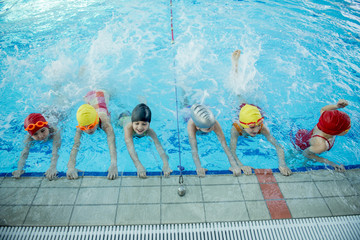 Instructor and group of children doing exercises near a swimming pool