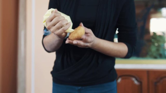 Pastry baker unrecognisable female hands squeezes creme out sleeve into profiterole over kitchen table