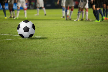 The soccer ball rests on the lawn while waiting for the footballer's ready.