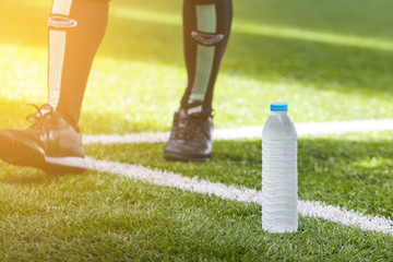Water on green soccer field with blurred player