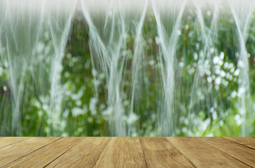 Empty top wooden table on blurred rain down from the roof for background