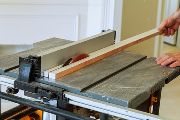 Unrecognizable handyman cutting wood circular saw in the new house