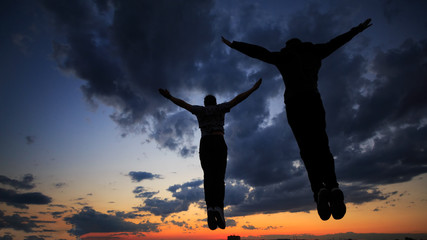 Silhouettes of two men on roof. Clouds and sunset