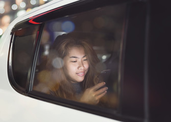 woman using phone inside car in city on night