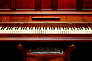 Fototapeta na wymiar Antique Piano - front view of piano keys and stool