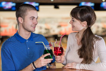 young smiling people drinking behind table in bowling club