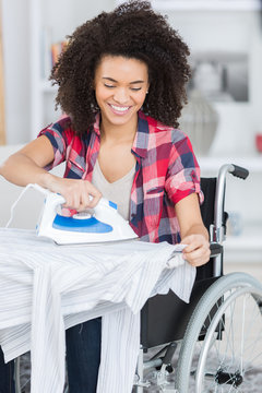 woman on wheelchair during ironing at home