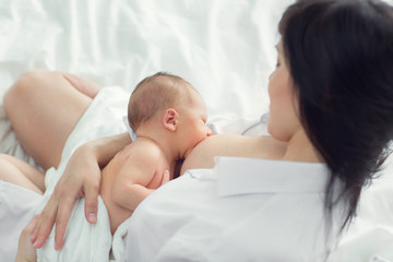 Fototapeta na wymiar Mother breastfeeding newborn in the bed