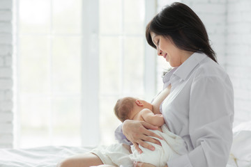 Mother breastfeeding newborn in the bed