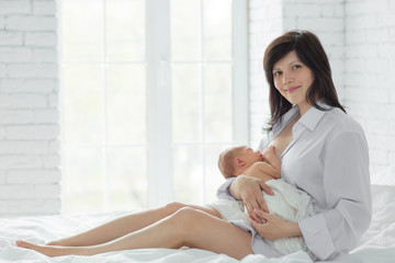 Mother breastfeeding newborn in the bed