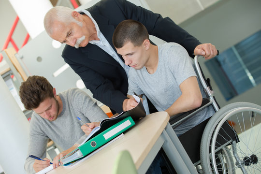 confident happy student in wheelchair working at office desk