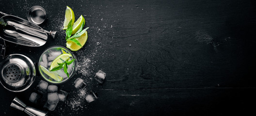 Lime and Mint cocktail, with ice, on a black wooden surface. Top view. Free space.