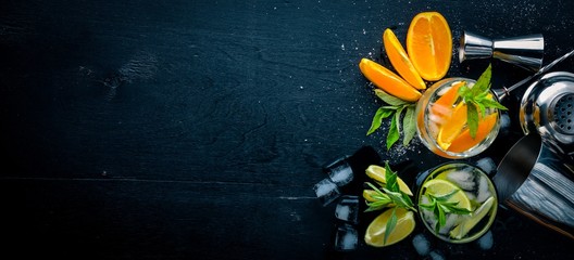 Cocktail of oranges and menthol with ice, on a black wooden surface. Top view. Free space.