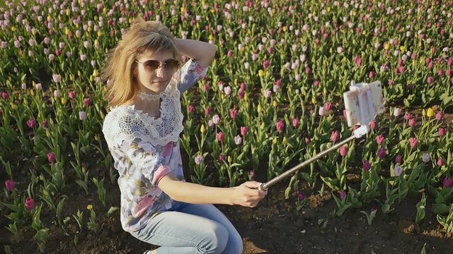 Young blonde girl making selfie at tulip field