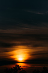 Vertical landscape of orange sky and sun shining from behind the