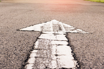 grunge white arrow on surface of traffic  road.