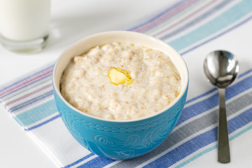 Oatmeal with a Pat of butter in a blue bowl on the table