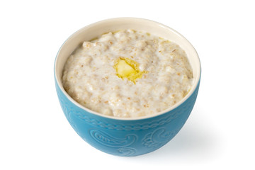 Porridge in a blue bowl with a piece of butter isolated on white background