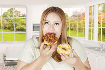 Obese woman eats two donuts at home