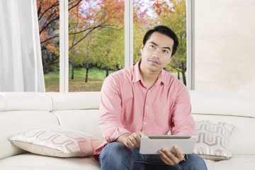 Obraz premium Pensive person uses tablet on the couch