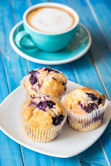 Blueberry muffins with freshly baked and fresh coffee on. Blue wooden table