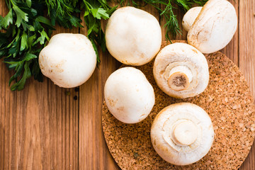 A few whole champignons and fresh parsley on a wooden table