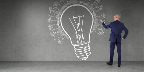 Businessman drawing a lightbulb on a wall 3D rendering