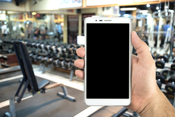 Man hand holding a smart phone in the fitness center.