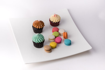 Colorful cupcakes and Macaroon on a white plate.