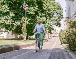 Businessman riding bicycle to work on urban street in morning. Lifestyle, transport, communication and people concept,