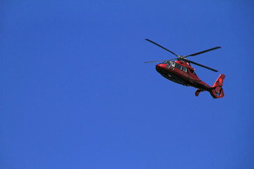 Fototapeta na wymiar Red helicopter flies in blue sky