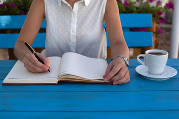 Obraz premium Young woman writing notes and drinking coffee