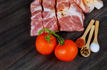 Raw pork bacon slices, rashers, spices, peppercorns, garlic, bay laurel leaves and red fresh cherry tomatoes
